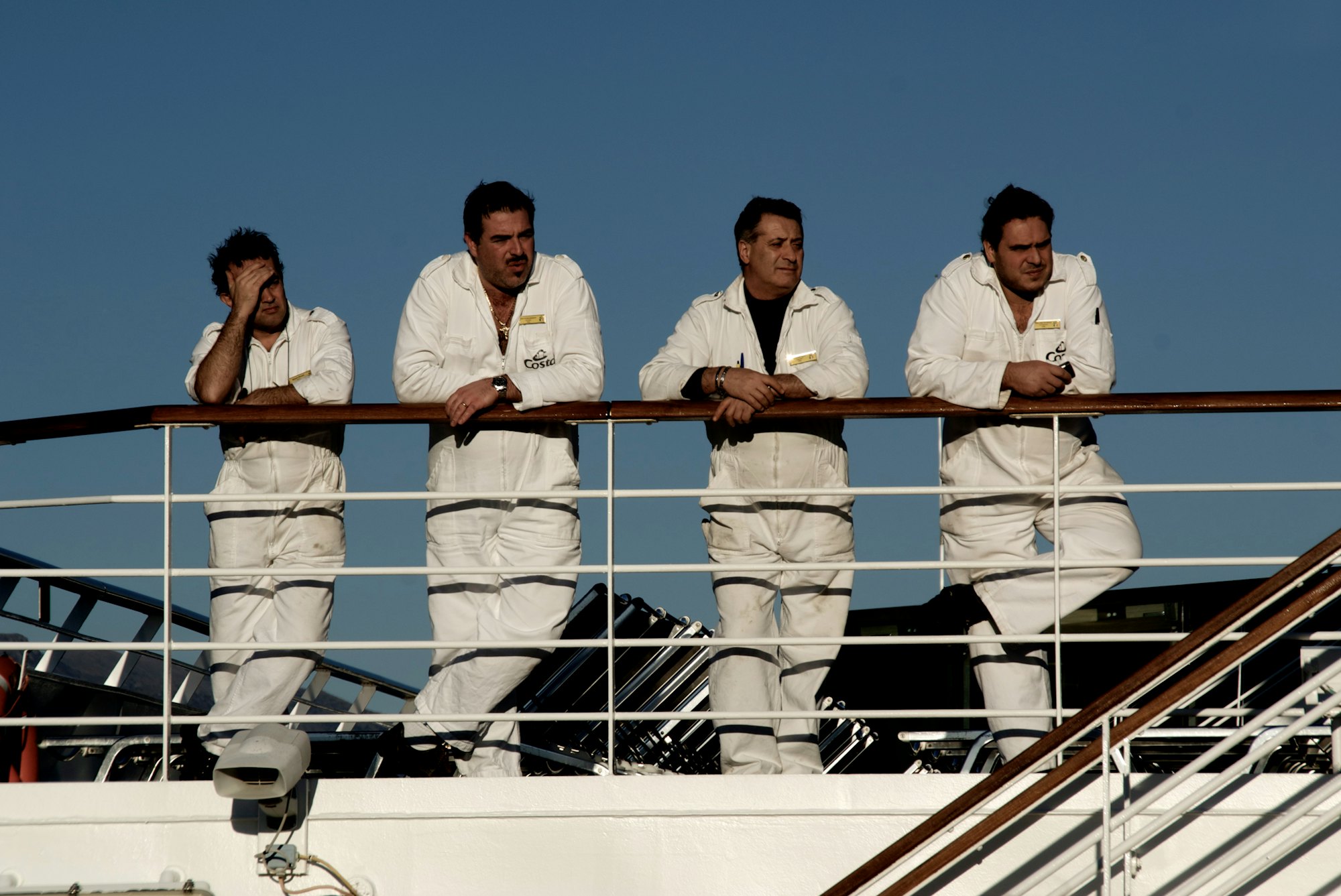 Four crew members in white uniforms on a ship's deck